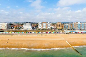A coastal cityscape with a beach, colorful beach huts, and high-rise residential buildings. - Hove Actually with spectacular seaviews iterally across the road from the Beach. (Hove)