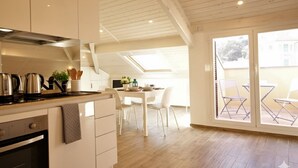 Une cuisine moderne avec des meubles blancs, une cuisinière et un coin repas comprenant une table et des chaises.