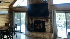 A spacious living room with a stone fireplace, a ceiling fan, and a large TV mounted on the wall. - Stunning Views from 3 Level Home, Majestic Sunrise and Mountain Scapes (Pine)