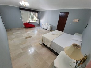 Relax in a stylish room with a made bed, bedside table, and comfortable chair.
