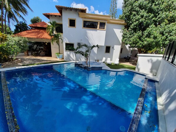 Relax by the serene pool surrounded by lush greenery and a well-maintained lawn.