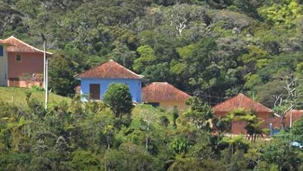 A cluster of houses on a hillside with a dense forest background. - Duplex apartment in a guesthouse in the Bocaina mountains with a view of the lake. (Bananal)