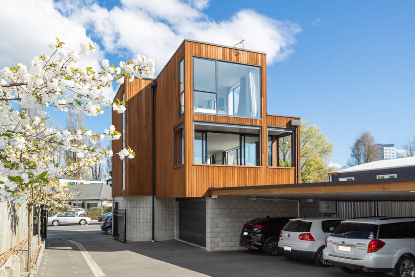 A modern two-story building with large windows and a garage.