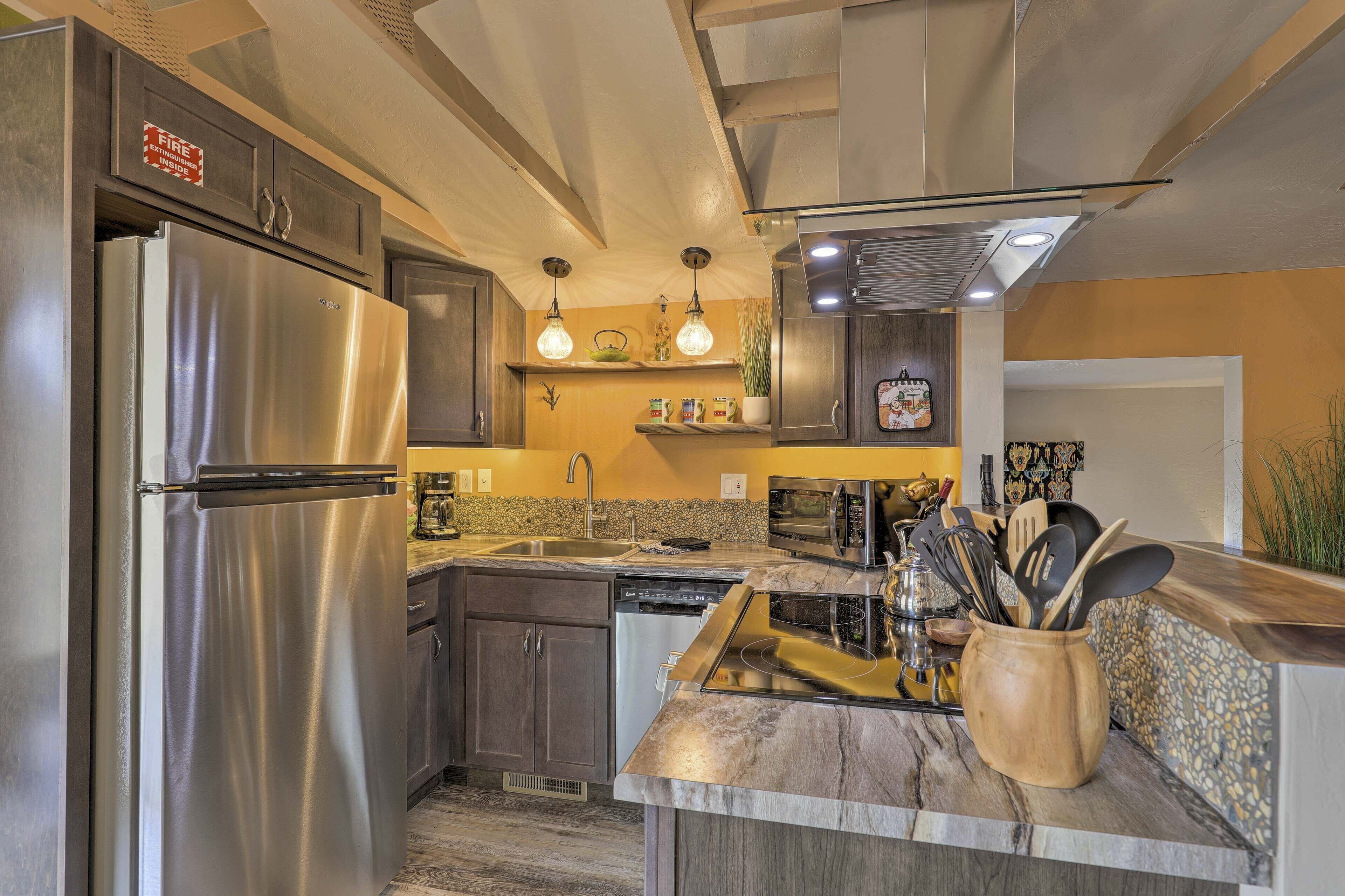 A modern kitchen with stainless steel appliances, granite countertops, and pendant lighting.
