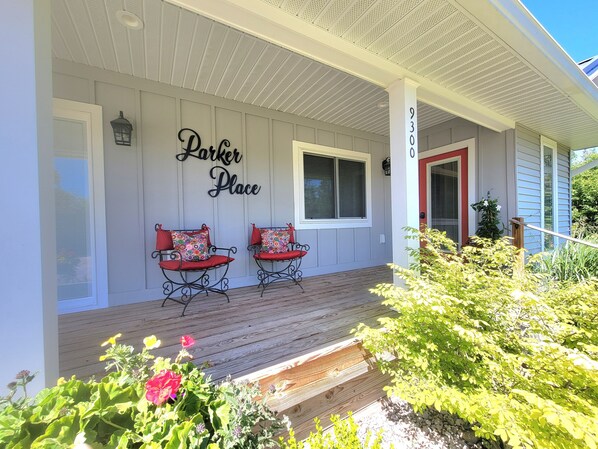 A porch with two chairs, a sign reading "Parker Place," and a red door.