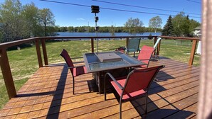 Um deck de madeira com uma mesa e cadeiras, com vista para um lago.