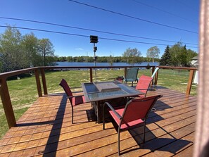 Enjoy a serene outdoor space with a deck overlooking the water, featuring a glass-top table and comfortable seating for four.