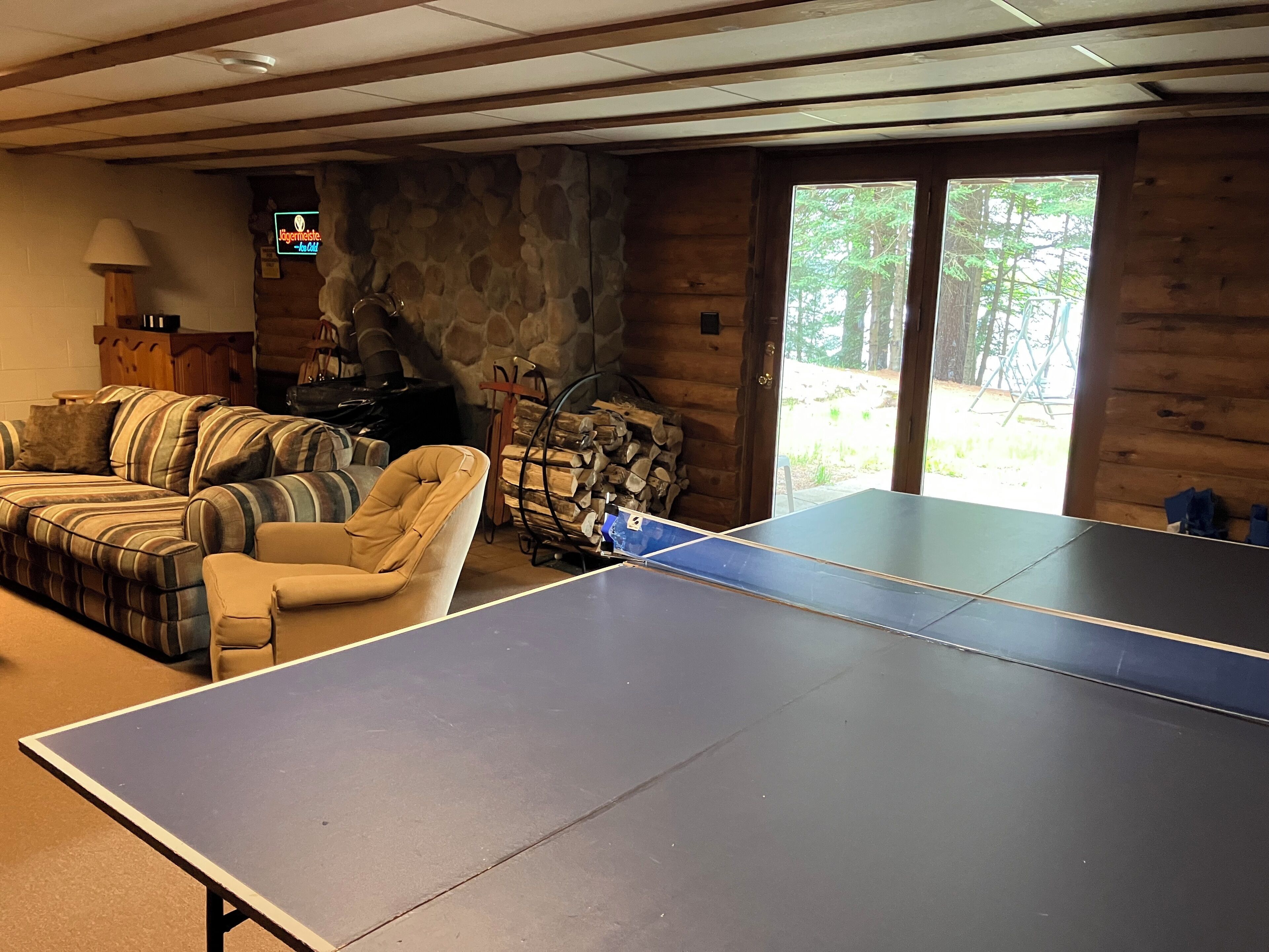 A ping pong table in a room with a stone wall, a sofa, and a fireplace.