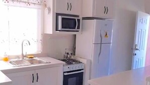 A modern kitchen with white cabinetry, a microwave, a refrigerator, and a stove.
