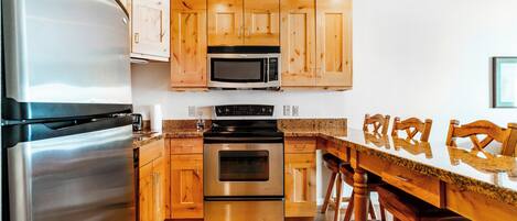 Una cocina moderna con electrodomésticos de acero inoxidable, gabinetes de madera y encimera de granito.