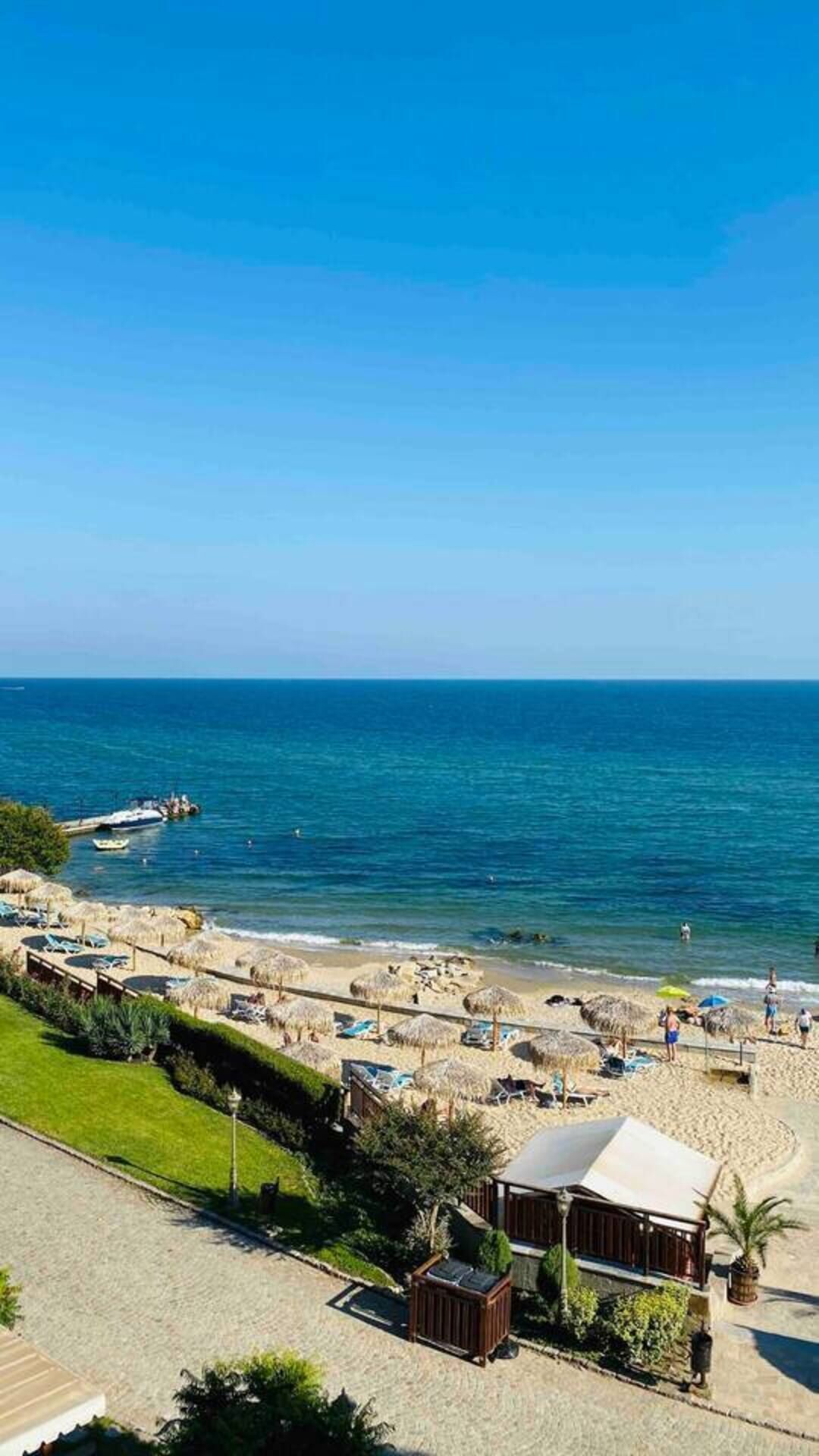 A beach resort with a view of the sea, a sandy beach, and a few umbrellas.