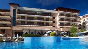 A hotel with multiple balconies, a swimming pool, and outdoor seating.