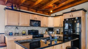 Eine Küche mit Holzausstattung, einem schwarzen Kühlschrank und einer Arbeitsplatte aus Granit.