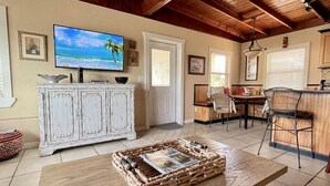 Ein Wohnzimmer mit Fernseher, einem weißen Schrank, einem Essbereich und einer Küchenzeile.