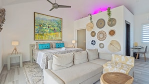 A modern hotel room with a bed, sofa, and decorative wall art.