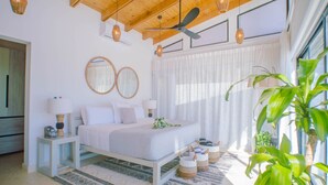 A bedroom with a bed, bedside tables, a ceiling fan, and a large window with curtains.