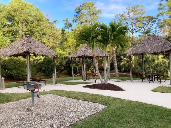 Un parque con construcciones de techo de paja, bancos y un camino de grava.