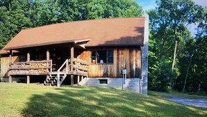 A rustic cabin with a wooden exterior, a porch, and a staircase leading to the entrance.
