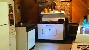 A compact kitchen with a refrigerator, stove, and a small countertop with various items.