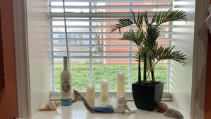 A kitchen window with a potted plant, candles, and decorative items. - Mermaid Landing Beachfront Condo with WIFI, Pools, and Hot Tub (Galveston)