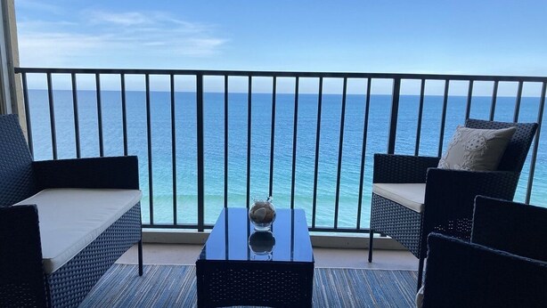 Un balcone con vista sull'oceano, arredato con un tavolo e due sedie.