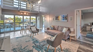 Uma sala de estar ampla com um sofá moderno, uma mesa de centro e um espaço de jantar com cadeiras e mesa.