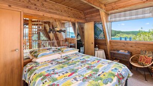 A cozy wooden cabin bedroom with a bed, a small table, and a chair.