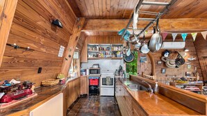 A compact kitchen with wooden walls, a central island, and a variety of cooking utensils and appliances.