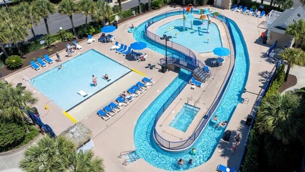A large pool with multiple sections, including a central water slide and a separate swimming area.