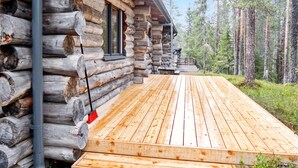 Une cabane en rondins avec une terrasse en bois et un tuyau en métal.