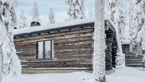 Une cabane en rondins entourée d’arbres couverts de neige.