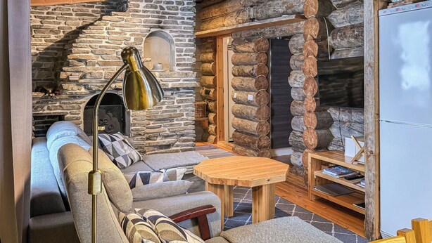 Une pièce chaleureuse avec un mur en pierre, un canapé, une table et une lampe.