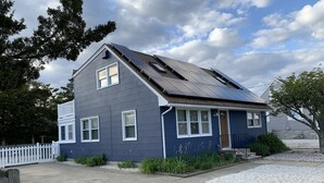 A two-story house with a dark blue exterior, white trim, and a sloped roof. - Newly renovated Cape Cod 4BR 2 Baths in LBI close to restaurants, and beach (Ship Bottom)