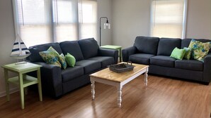 A living room with two dark sofas, a wooden coffee table, and a small side table. - Newly renovated Cape Cod 4BR 2 Baths in LBI close to restaurants, and beach (Ship Bottom)