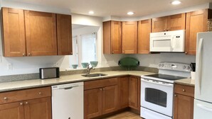 A modern kitchen with wooden cabinets, a built-in microwave, a stove, and a dishwasher. - Newly renovated Cape Cod 4BR 2 Baths in LBI close to restaurants, and beach (Ship Bottom)