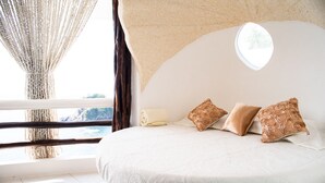 A bedroom with a large bed, a window with curtains, and a view of the outdoors.