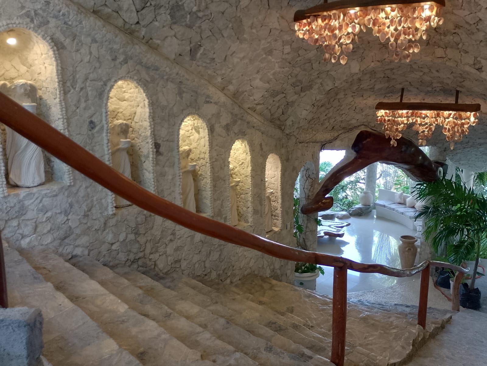 Una escalera de piedra con barandilla de madera que lleva a una zona de estar con vistas a un jardín.
