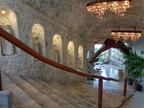 A stone staircase with a wooden handrail leading to a seating area with a view of a garden.