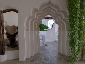 A corridor with white walls, stone flooring, and a decorative archway.