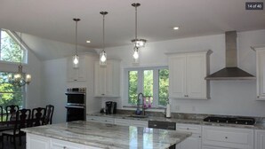 Une cuisine moderne avec des meubles blancs, un grand îlot central et des luminaires suspendus.