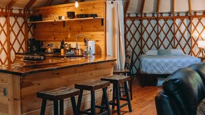 Interieur van een joert, met houten afwerking, een centraal gelegen keuken en zithoek.