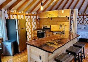 Una cocina compacta con una isla central, un refrigerador, una estufa y un lavamanos.