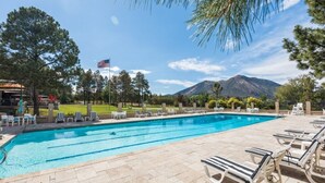 Une piscine avec des chaises longues, un drapeau américain et des montagnes en arrière-plan.