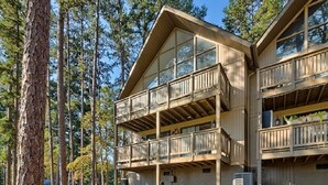 A two-story wooden cabin with balconies, surrounded by tall pine trees. - Keowee Key ~ Cozy Condo ~ Golf Course View - Amenities (Salem)