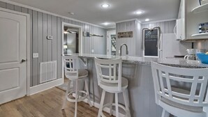 A kitchen with white bar stools, a refrigerator, and a chalkboard with writing. - Keowee Key ~ Cozy Condo ~ Golf Course View - Amenities (Salem)