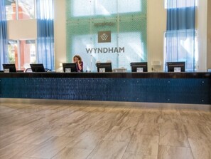 Ein Empfangsschalter mit einem Schild mit der Aufschrift "WYNDHAM" und einer gefliesten Wand dahinter.