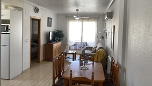 Un espace de vie compact comprenant un coin repas, une kitchenette et un balcon.