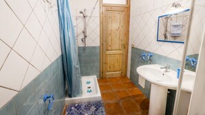 Ein Badezimmer mit Dusche, Waschbecken und einer Holztür.