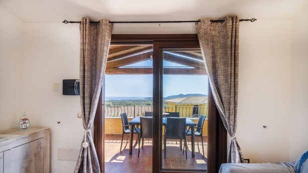 Ein Zimmer mit einer Schiebetür zu einer Terrasse im Freien, komplett mit Tisch und Stühlen.