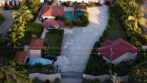 Vista aérea de una zona residencial costera con casas, una piscina y palmeras.
